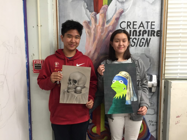 Juniors Joshua Yuan (left) and Ashley Guan (right) stand with their winning pieces during an Art Club meeting, in which the top three voted pieces were announced.